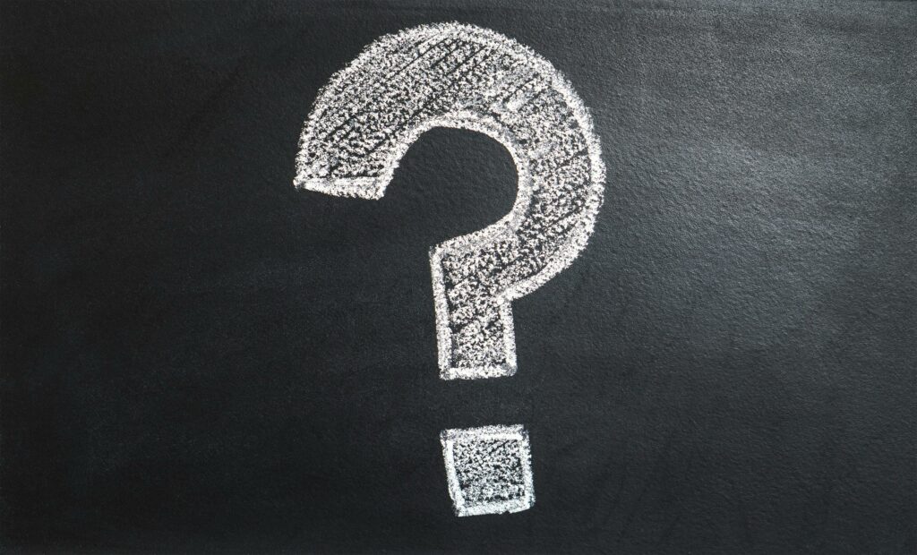 Point d'interrogation blanc à la craie sur un tableau noir par rapport aux questions sur les services et besoins internet et informatiques de la page contact. Contactez nous.